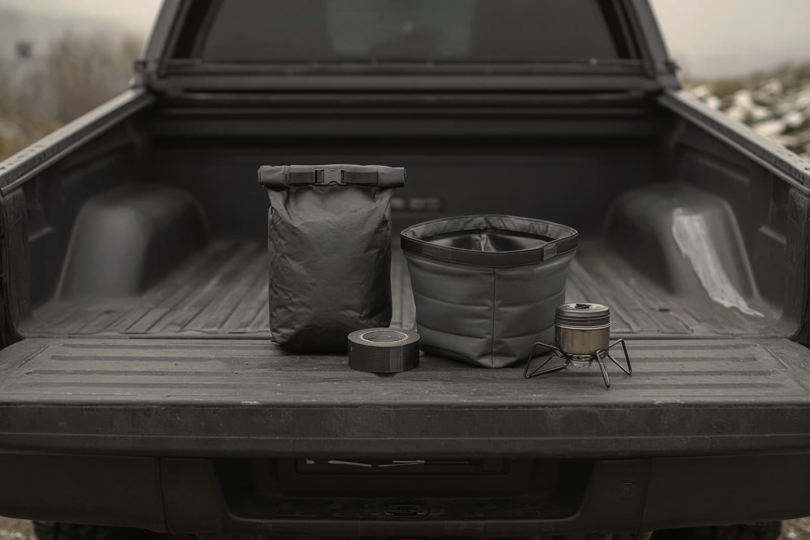 A tailgate holding a small dry bag, a roll of repair tape, collapsible wash bins and a tiny backup stove