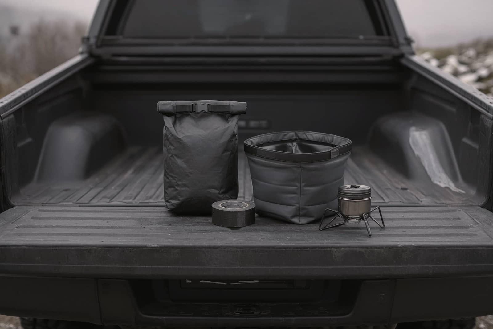 A tailgate holding a small dry bag, a roll of repair tape, collapsible wash bins and a tiny backup stove