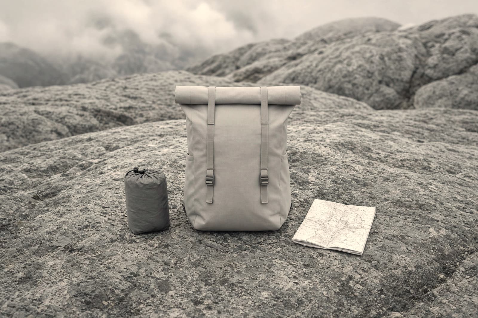 A minimal frameless roll-top ultralight pack on an alpine granite slab with a small trimmed kit
