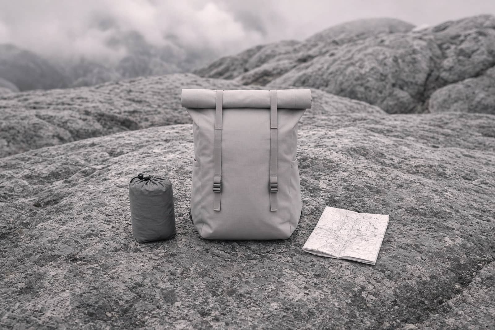 A minimal frameless roll-top ultralight pack on an alpine granite slab with a small trimmed kit