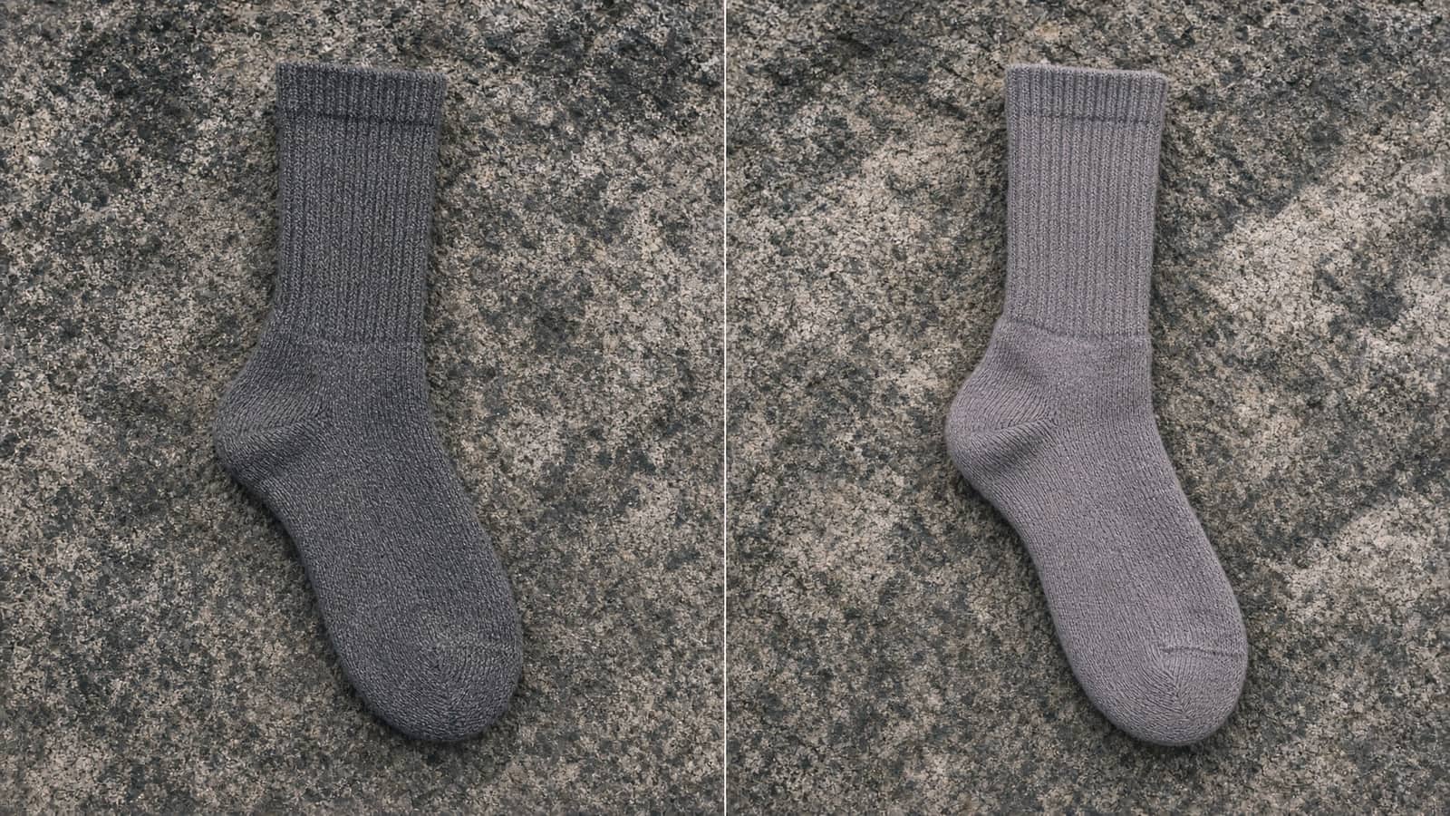 A dense-knit crew hiking sock beside a cushioned crew merino sock, granite slab
