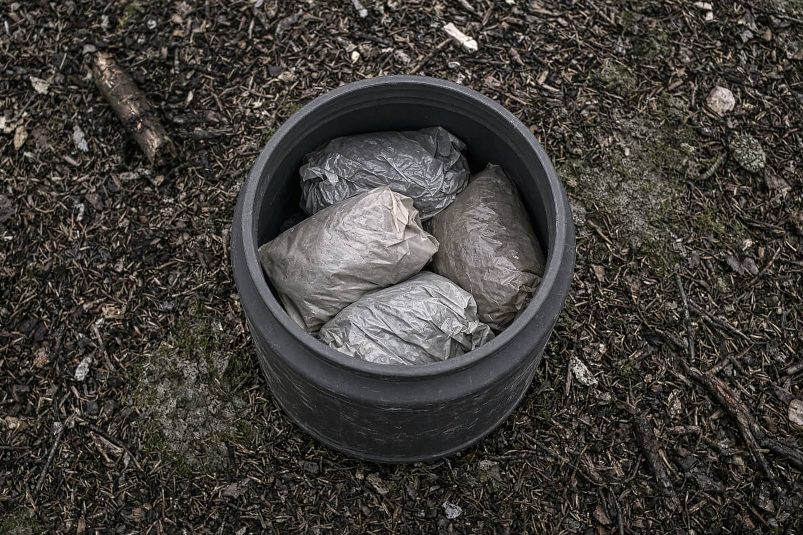 Food bags being packed into an open bear canister, top-down