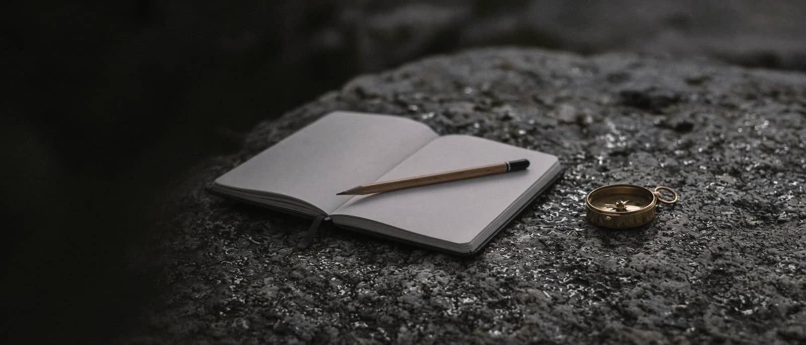 A field notebook, pencil and compass on granite, macro