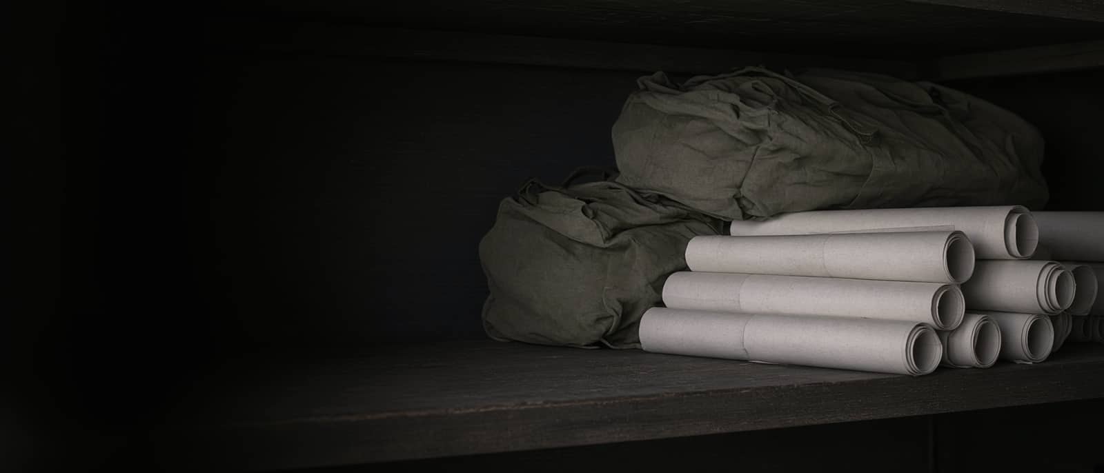 A shelf of rolled maps and gear bags in low light