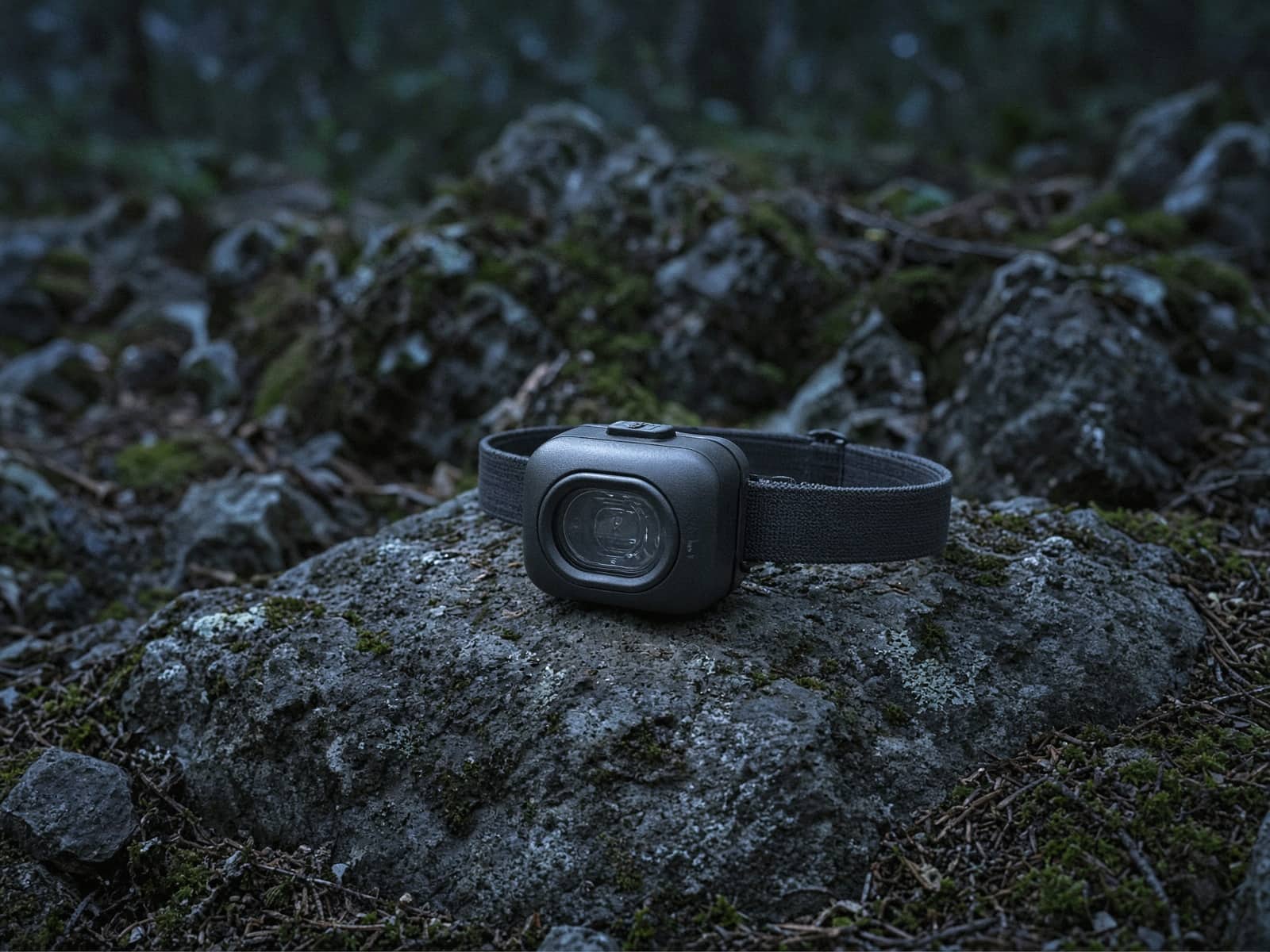 A compact rechargeable headlamp on a rock at blue hour