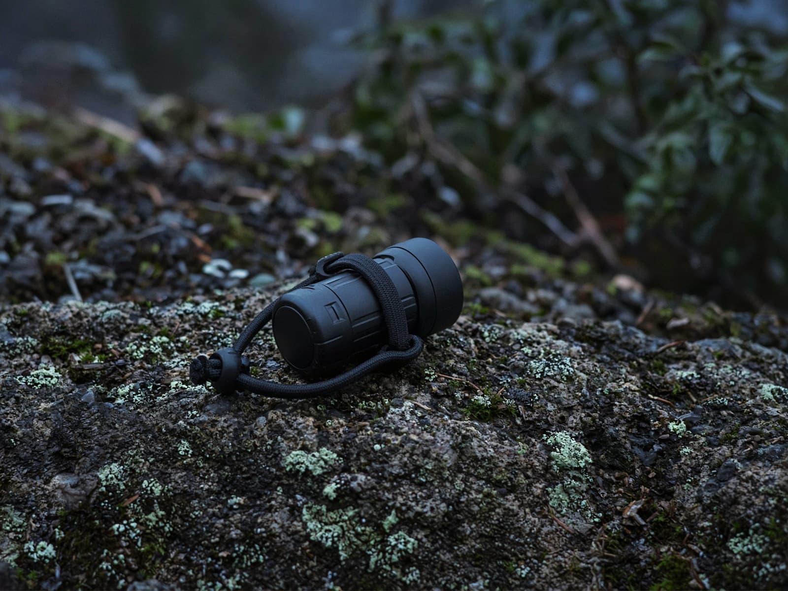 A tiny camp headlamp with a cord band on a rock at blue hour