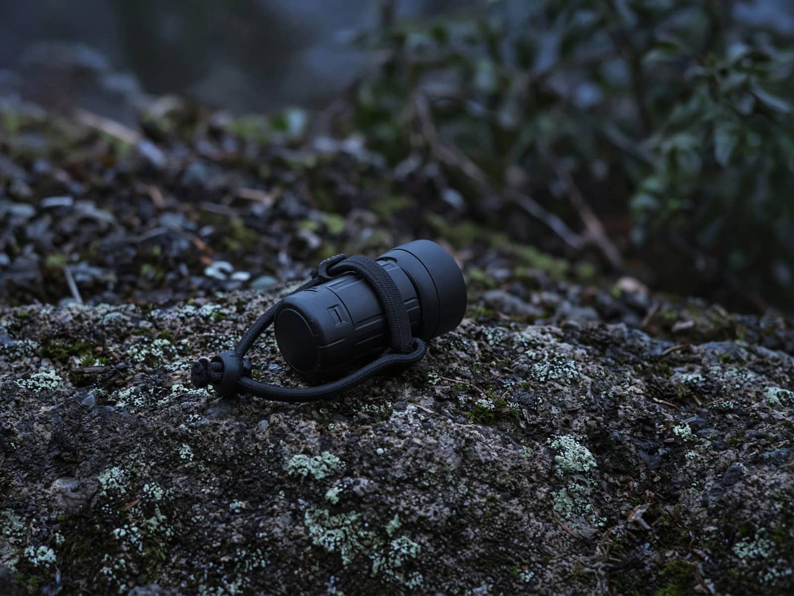 A tiny camp headlamp with a cord band on a rock at blue hour