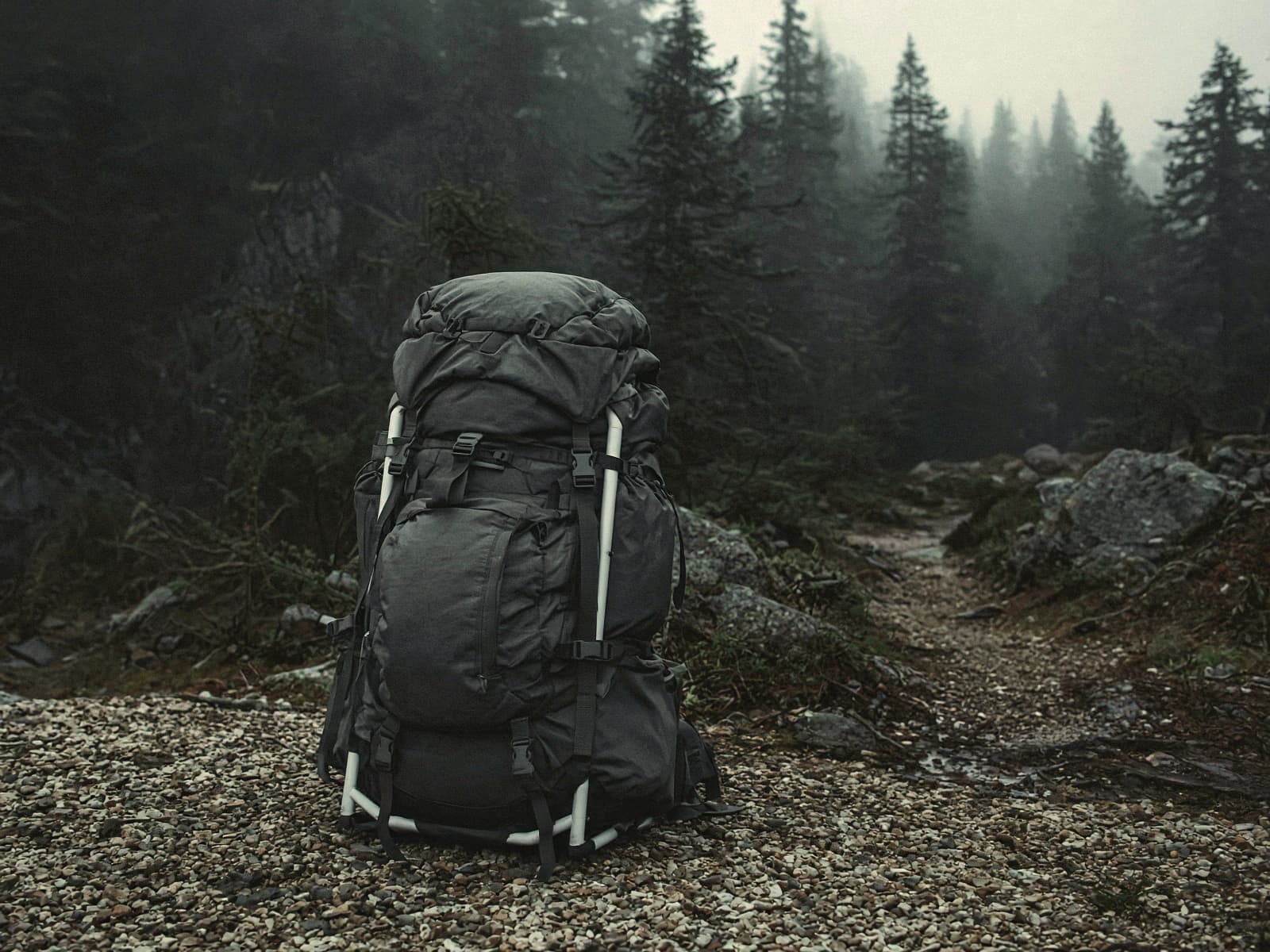 A light framed 60-liter pack standing on trailhead gravel