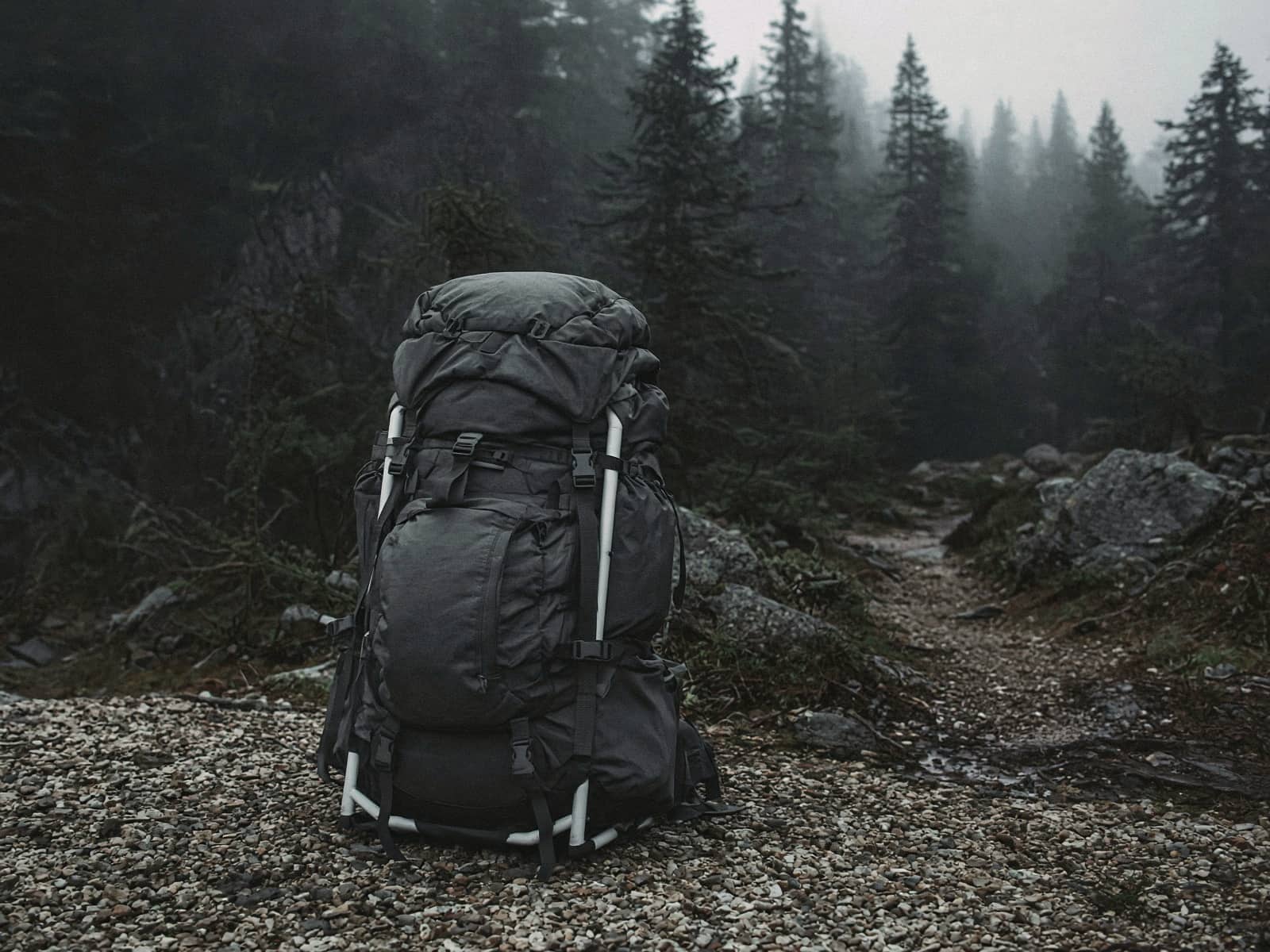 A light framed 60-liter pack standing on trailhead gravel