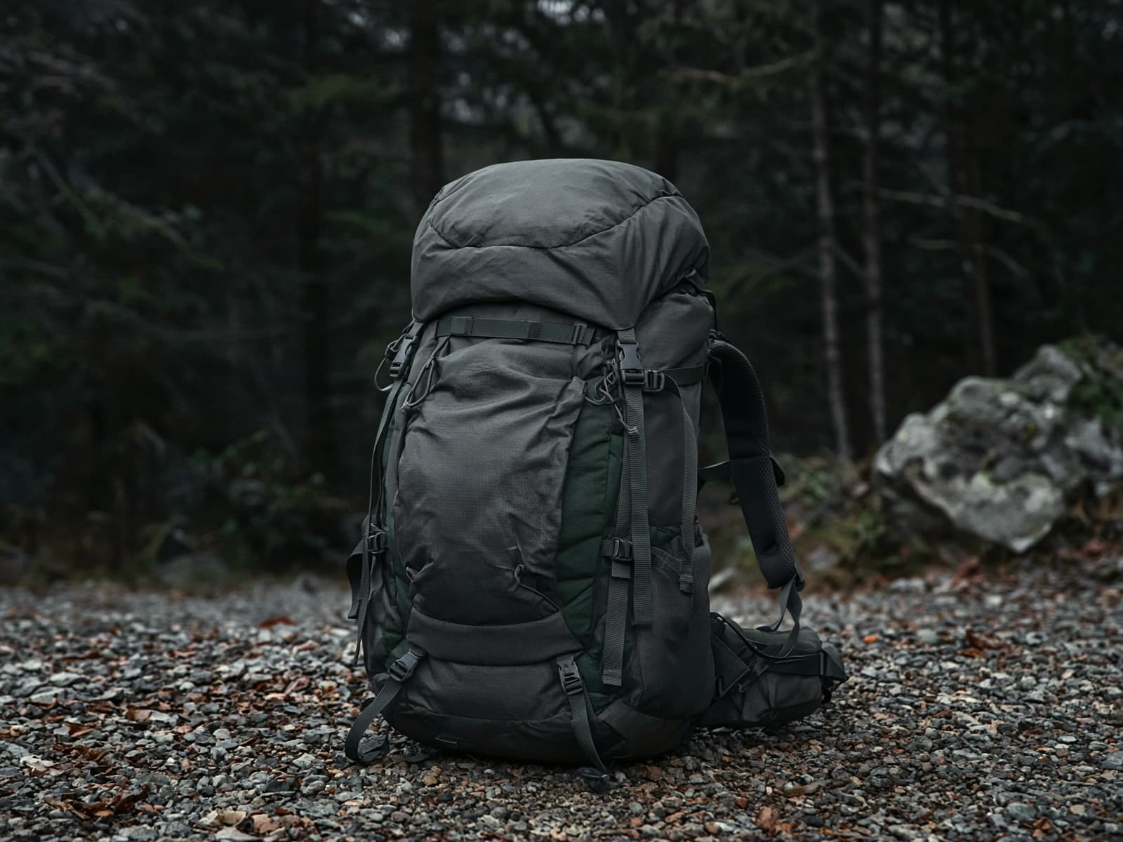 A women's supportive 60-liter pack standing on trailhead gravel