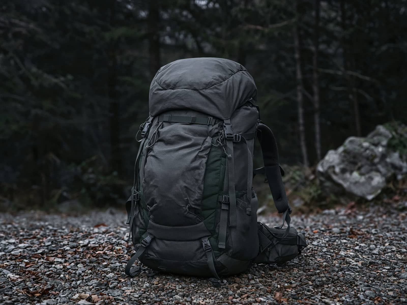 A women's supportive 60-liter pack standing on trailhead gravel