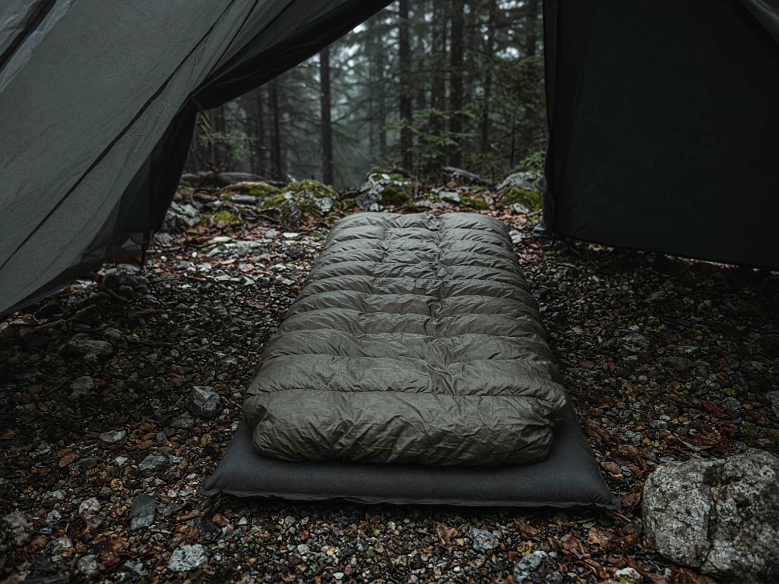 A sewn-footbox down quilt lofted on a pad inside a tent