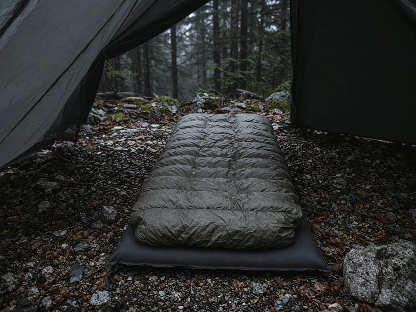 A sewn-footbox down quilt lofted on a pad inside a tent