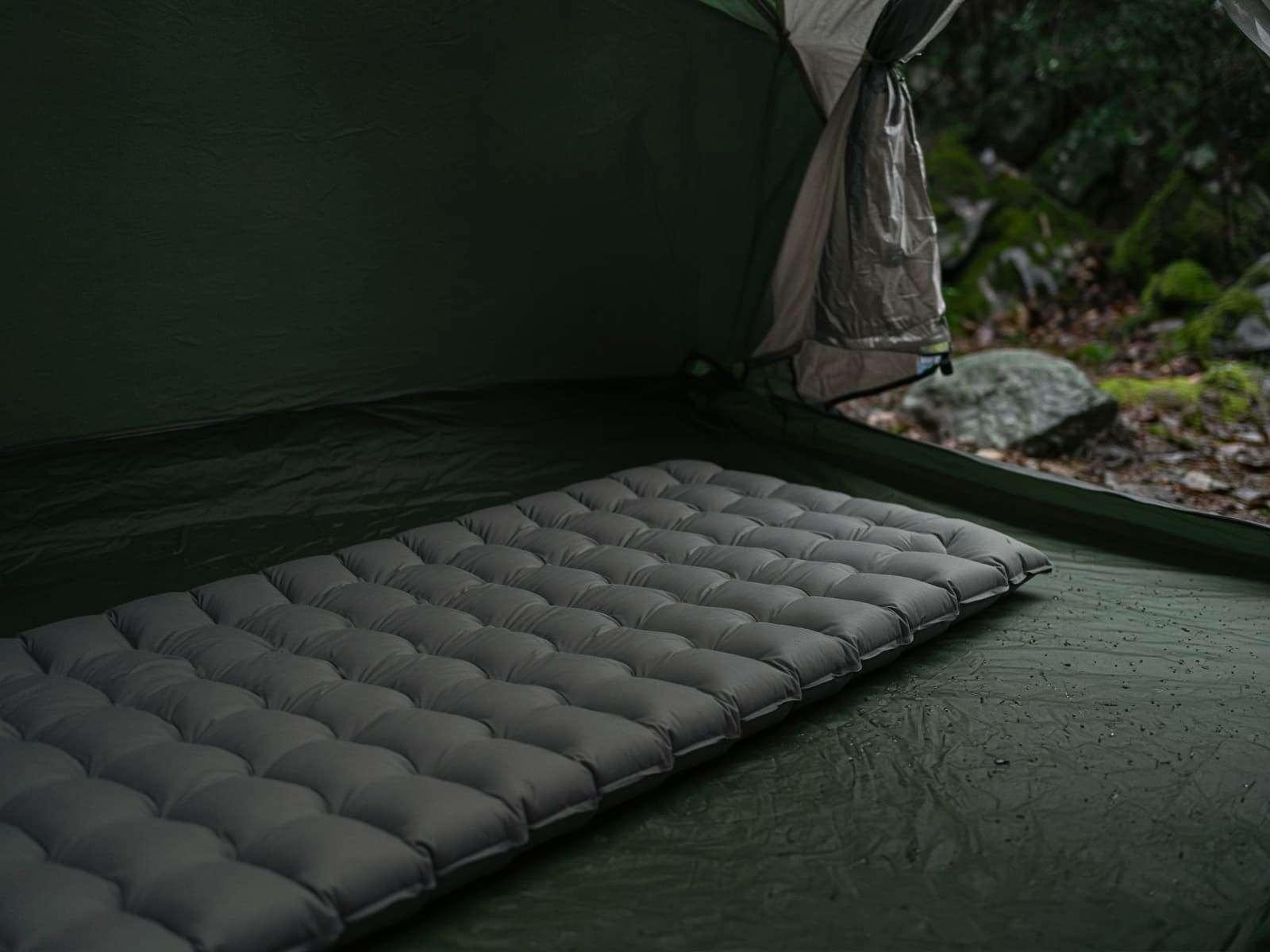 A tough-fabric insulated air pad on a tent floor