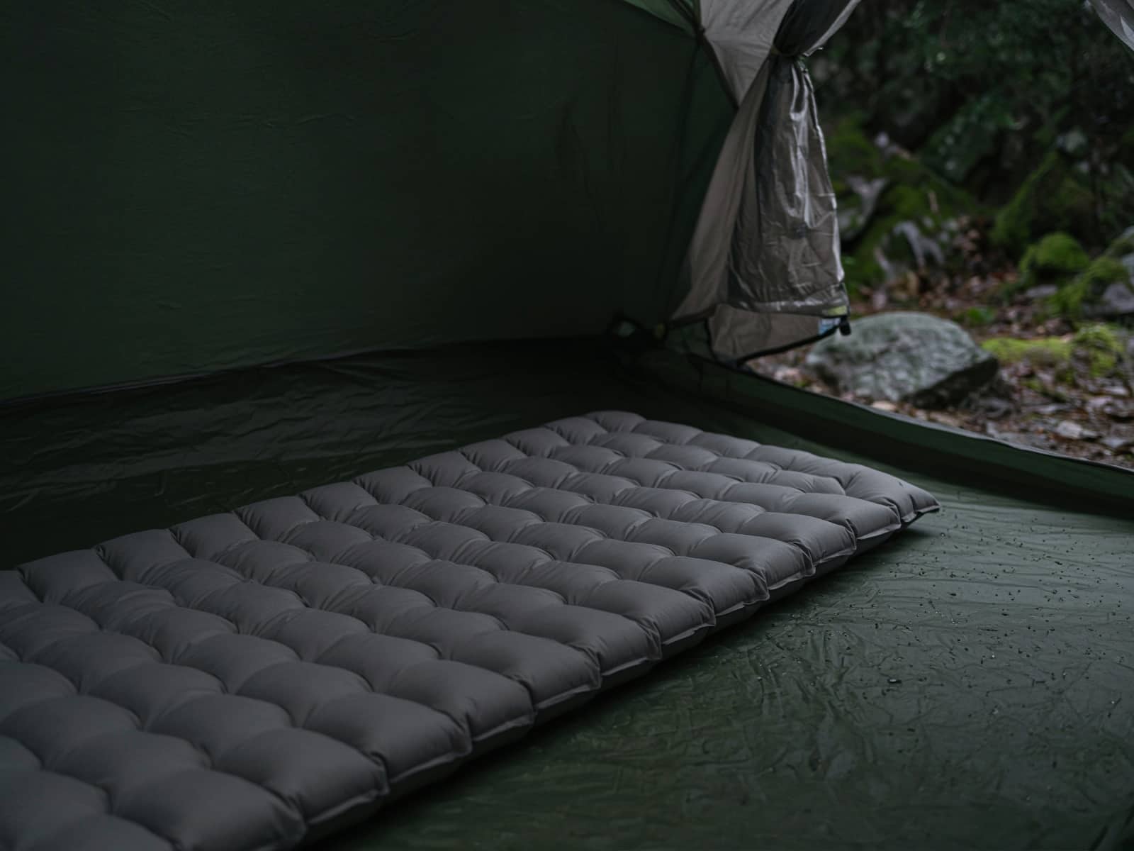 A tough-fabric insulated air pad on a tent floor
