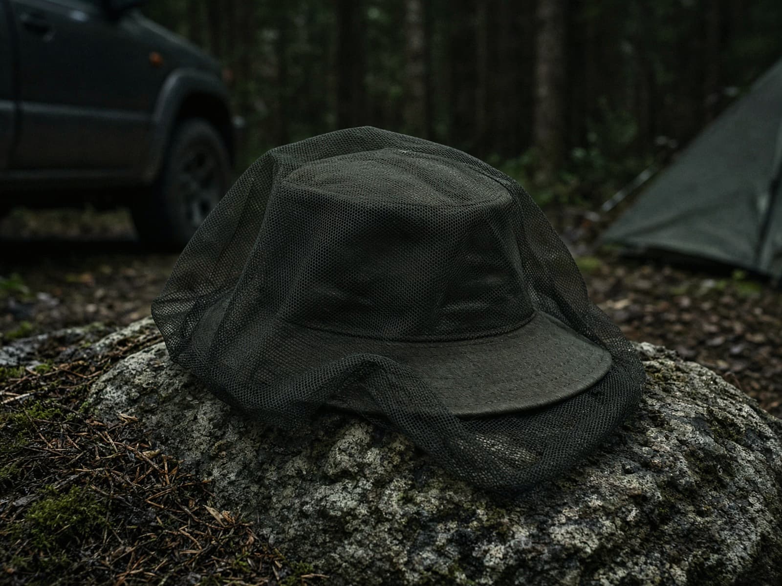 A mesh bug head net over a hat at a car campsite