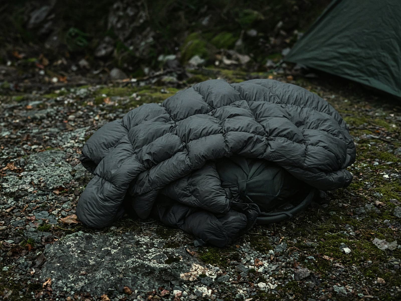 A synthetic quilted puffy draped over a pack at a cold camp