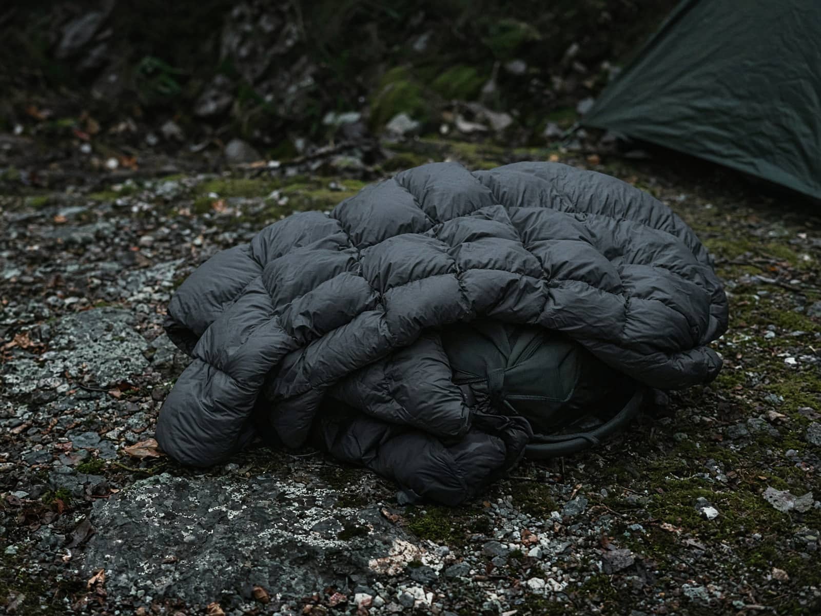 A synthetic quilted puffy draped over a pack at a cold camp