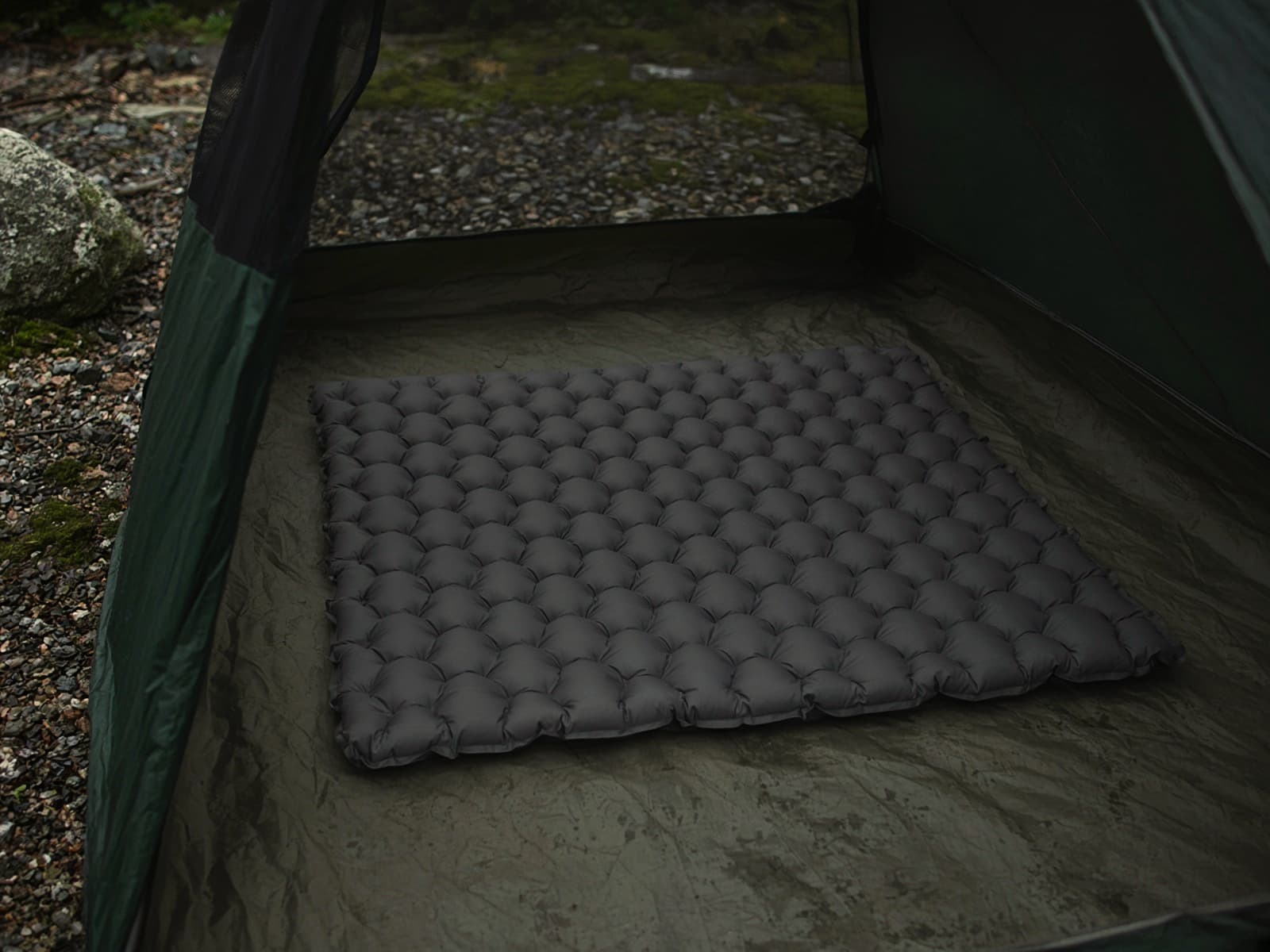 A rectangular quilted air pad on a tent floor
