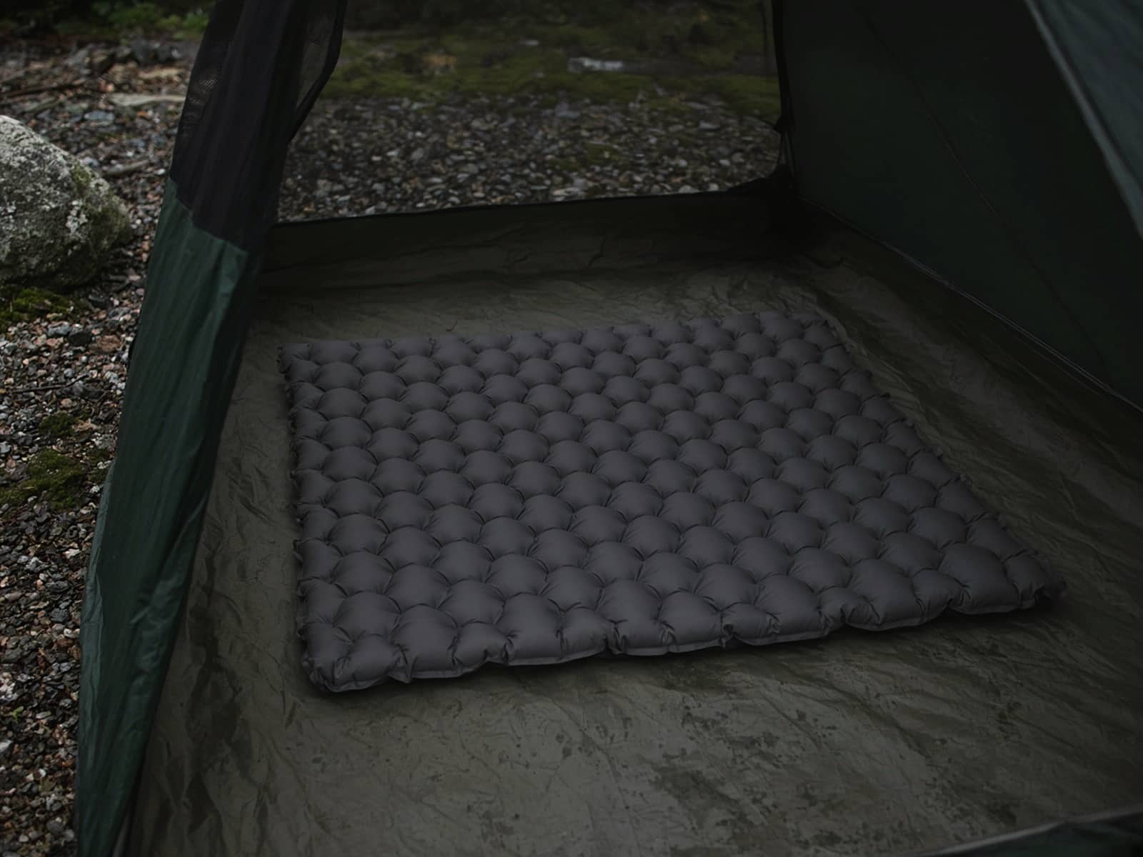 A rectangular quilted air pad on a tent floor