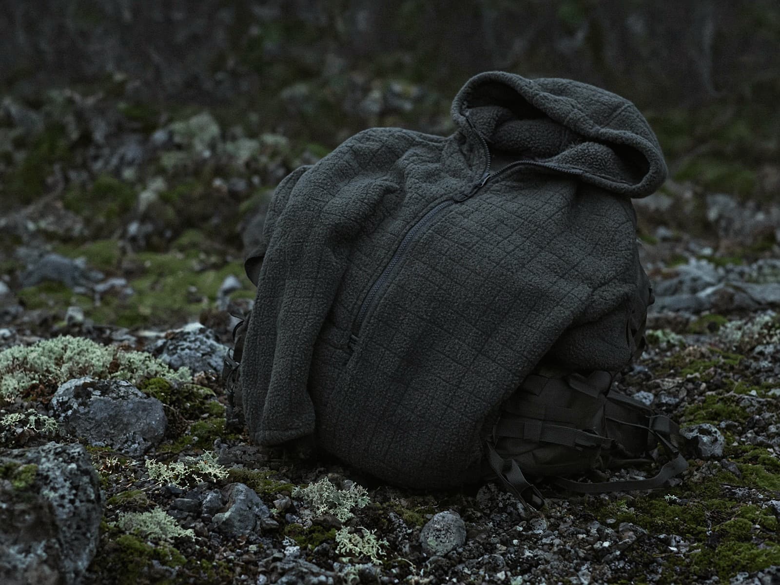 A zip grid-fleece hoody draped over a pack at a cold camp