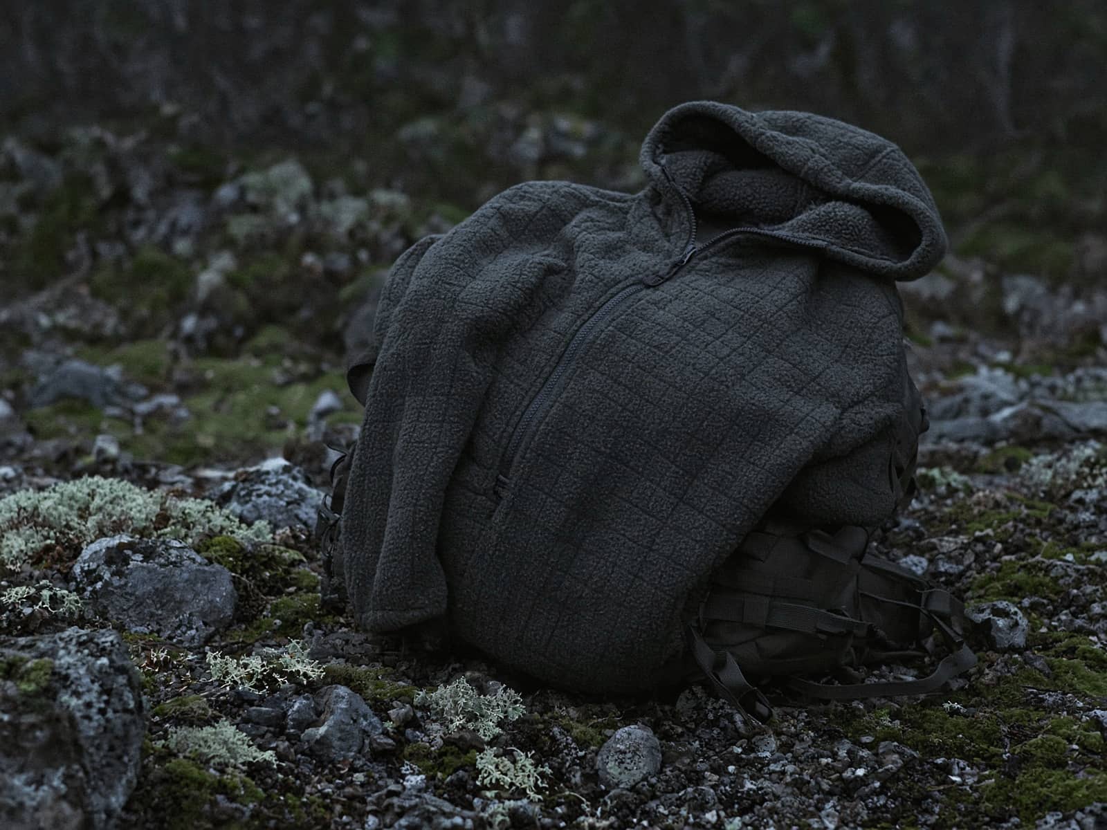 A zip grid-fleece hoody draped over a pack at a cold camp