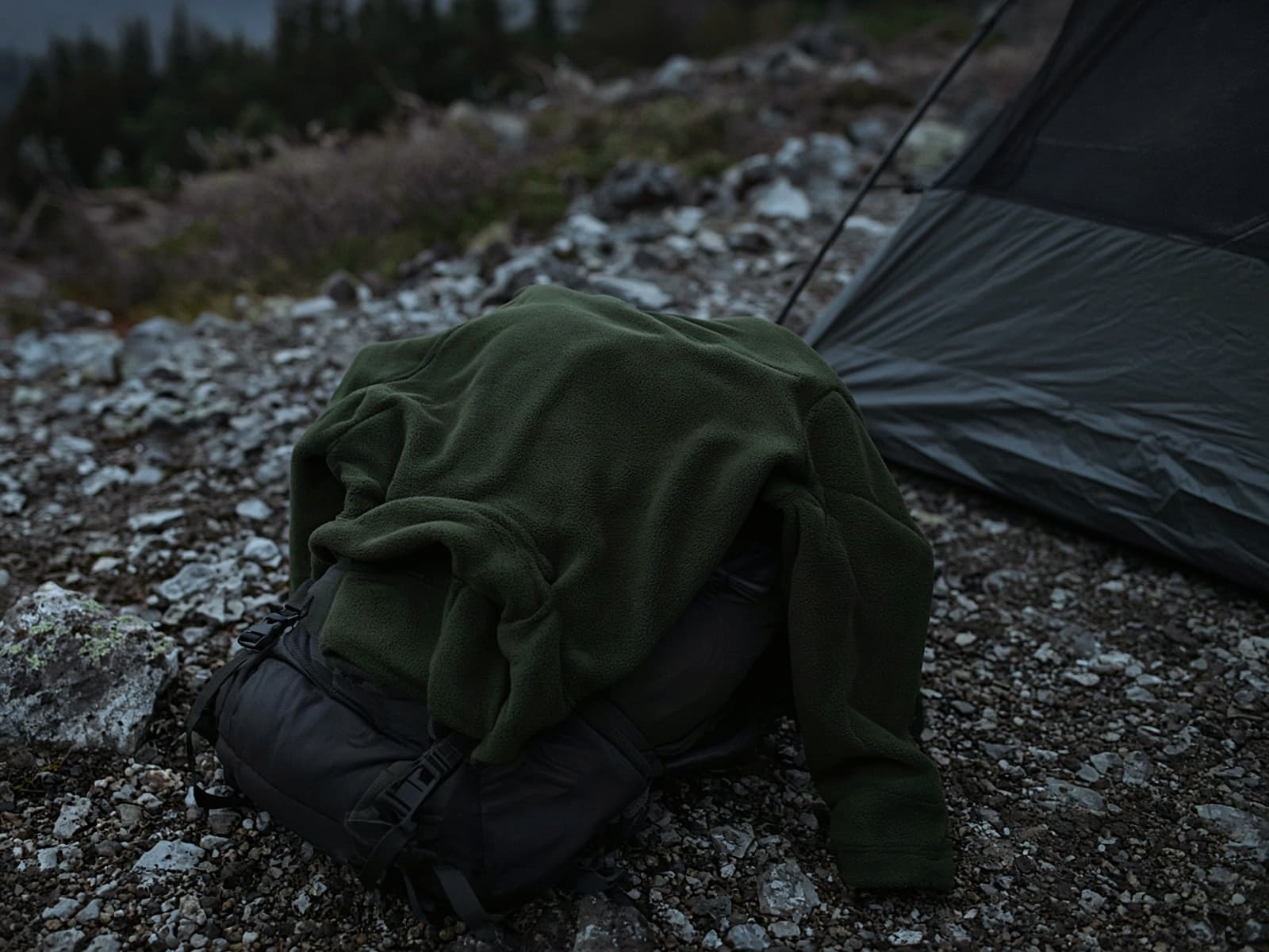 A basic hiking fleece draped over a pack at a cold camp