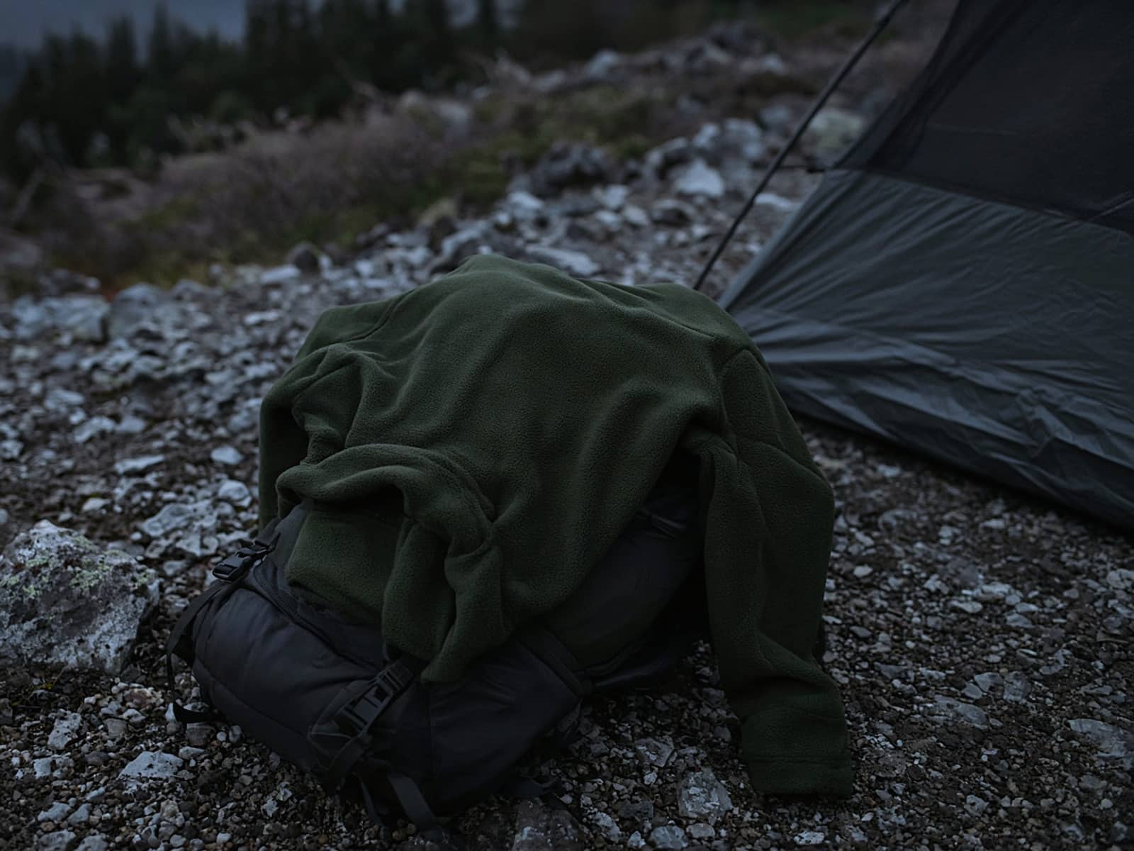 A basic hiking fleece draped over a pack at a cold camp