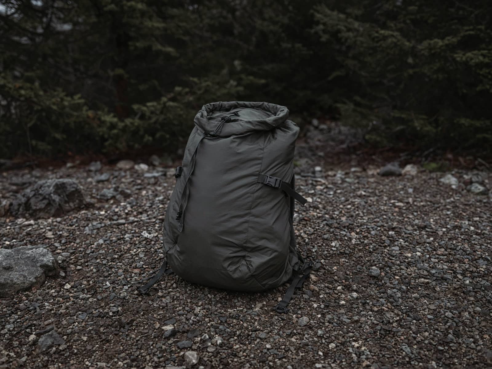 A simple framed ultralight pack standing on trailhead gravel